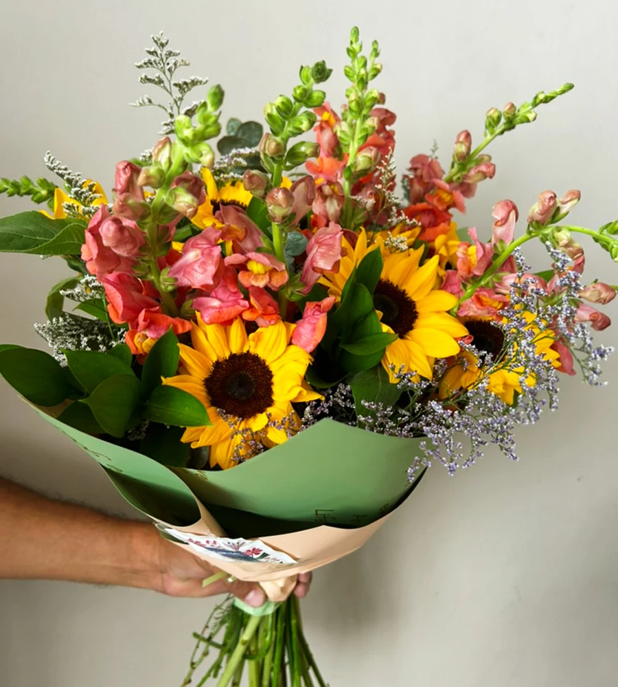 Bouquet con girasoles, flores coral y follaje verde